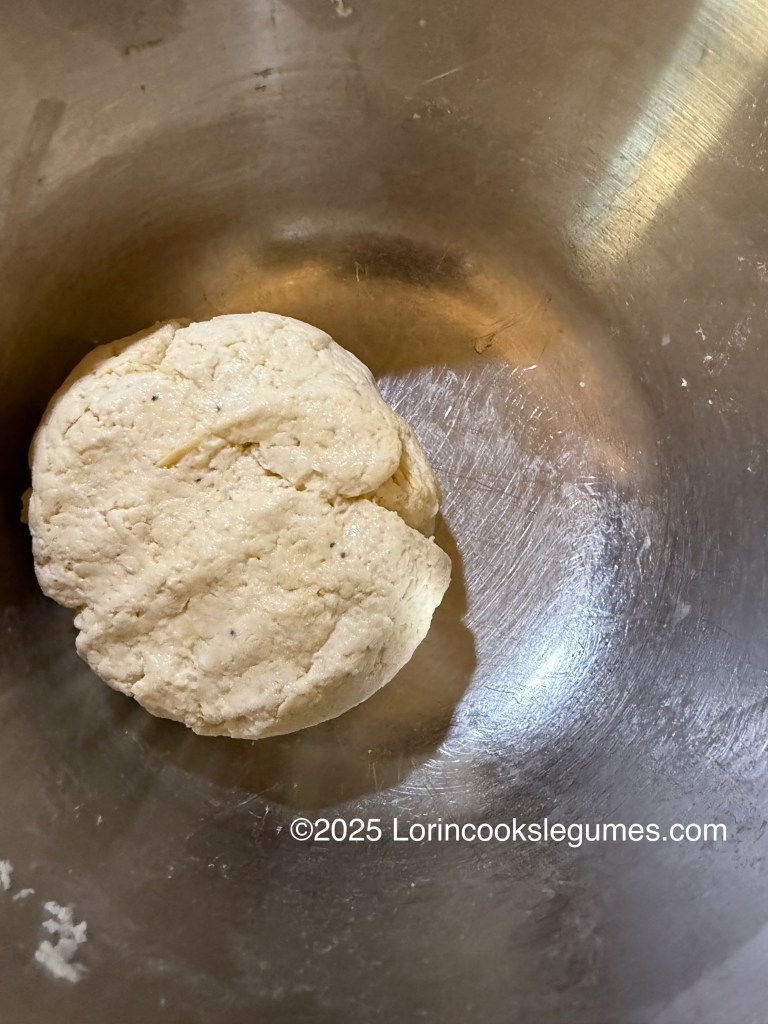 A dough ball made from plantains and other ingredients resting in a mixing bowl.
