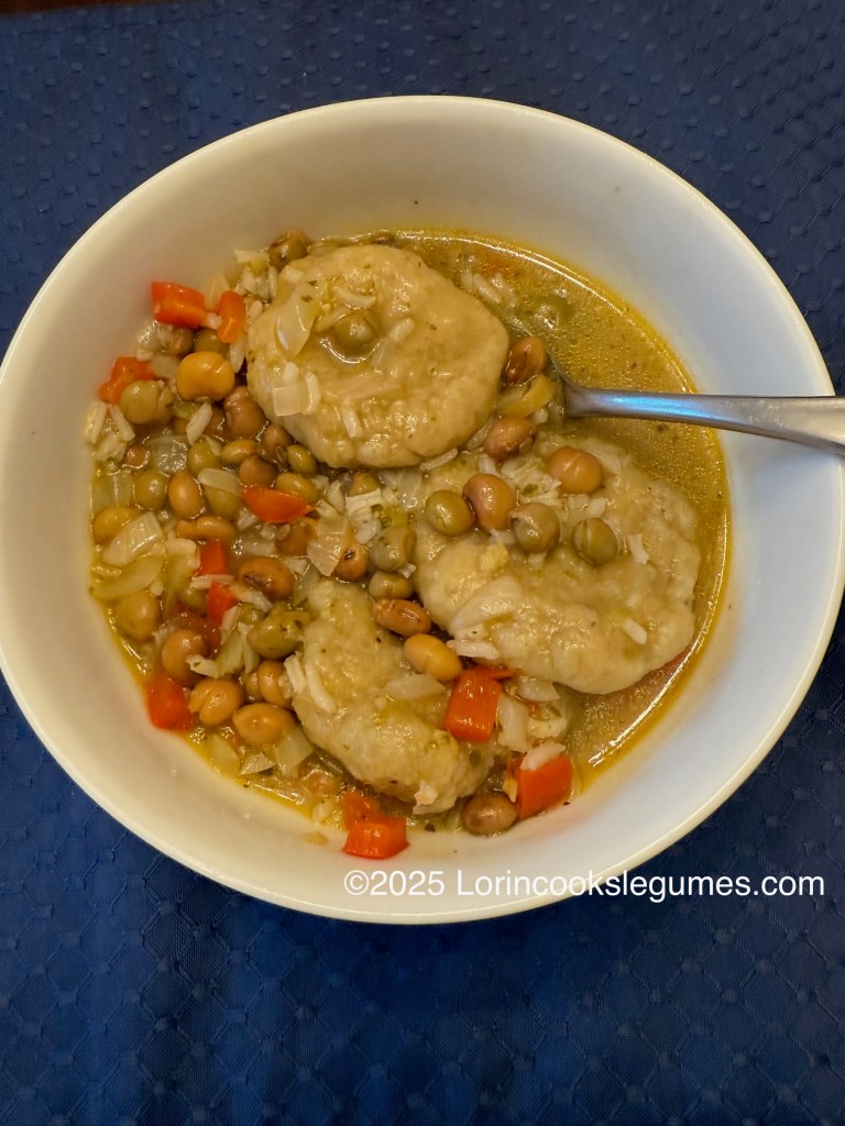 Bowl of asopao with plantain dumplings, pigeon peas, and diced vegetables in a broth.