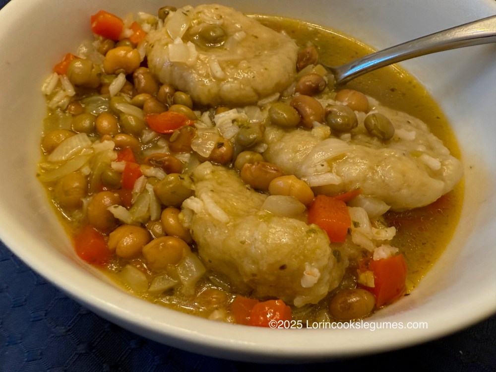 A bowl of Asopao de Gandules, featuring dumplings, rice, and pigeon peas, with diced red bell peppers and onions, served in a flavorful broth.
