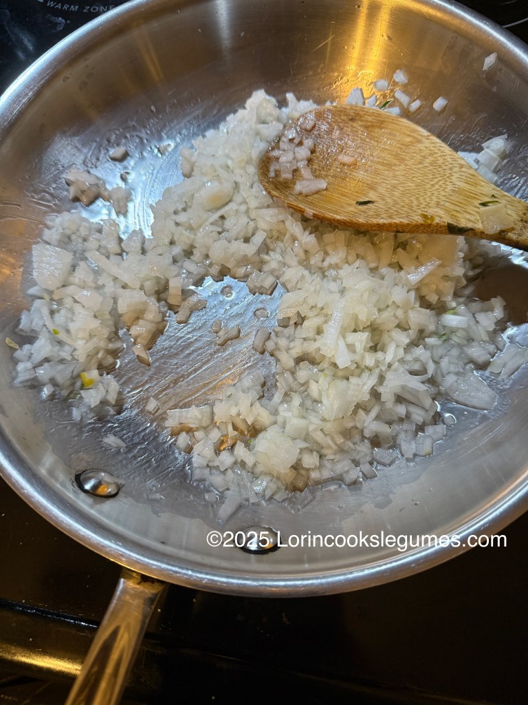 Sauteed chopped onions in a stainless steel pan with a wooden spoon.