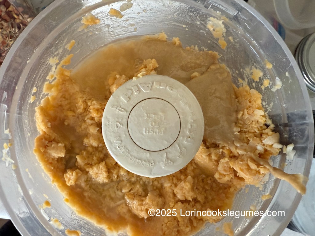 A food processor containing ground chickpeas and tahini for making hummus.