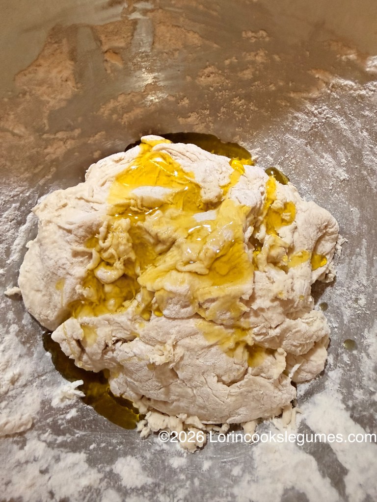 Close-up of a ball of dough with oil poured over the top, in a mixing bowl.