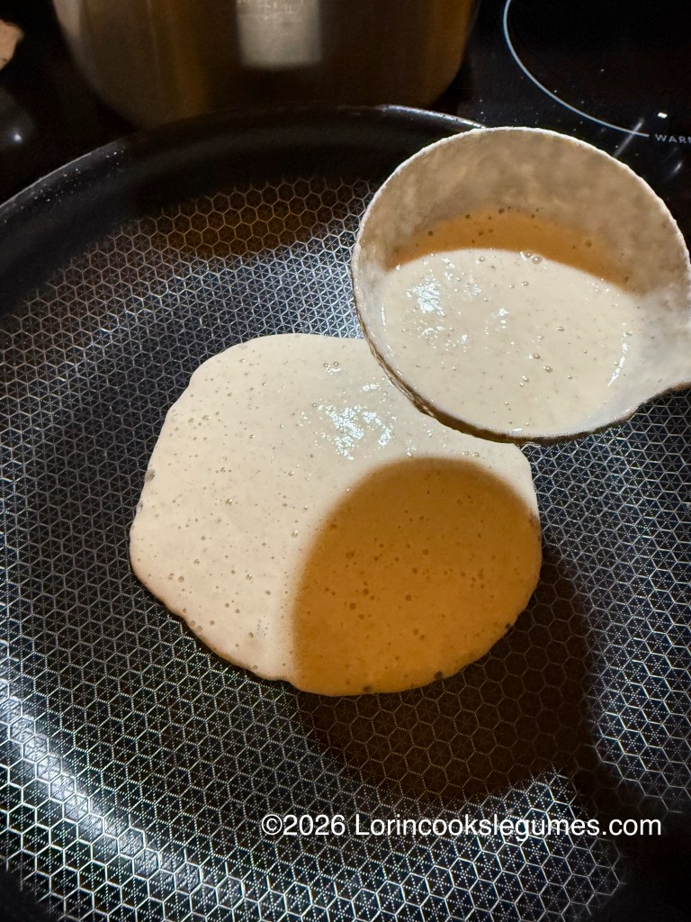 A ladle pouring batter onto a non-stick frying pan to make a canjeero.