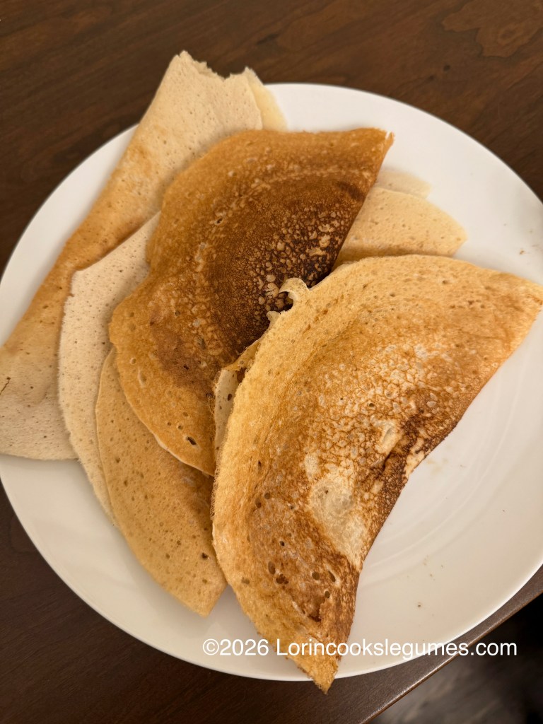 A plate of folded canjeero pancakes in various shades of brown.