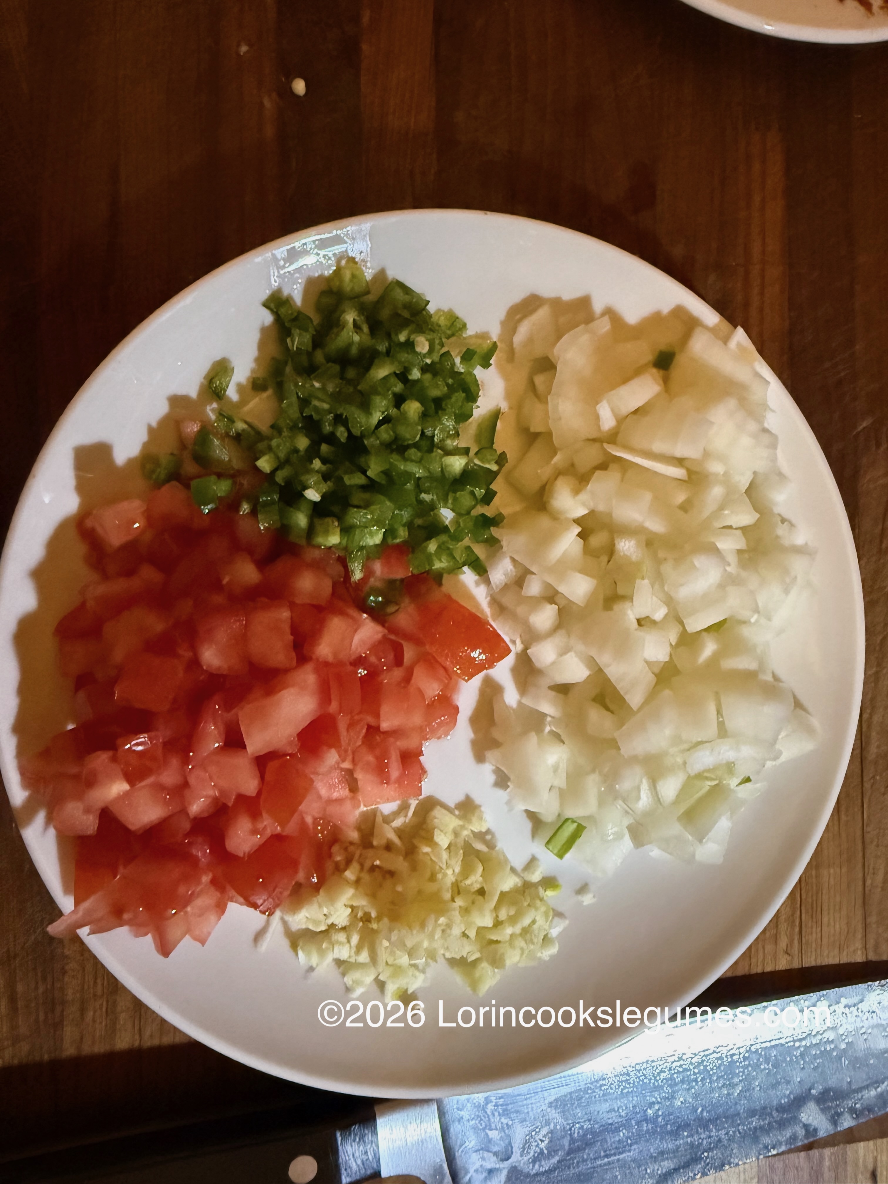 Chopped tomatoes, onions, jalapeño, and minced garlic on a plate. ©2026 Lorincookslegumes.com