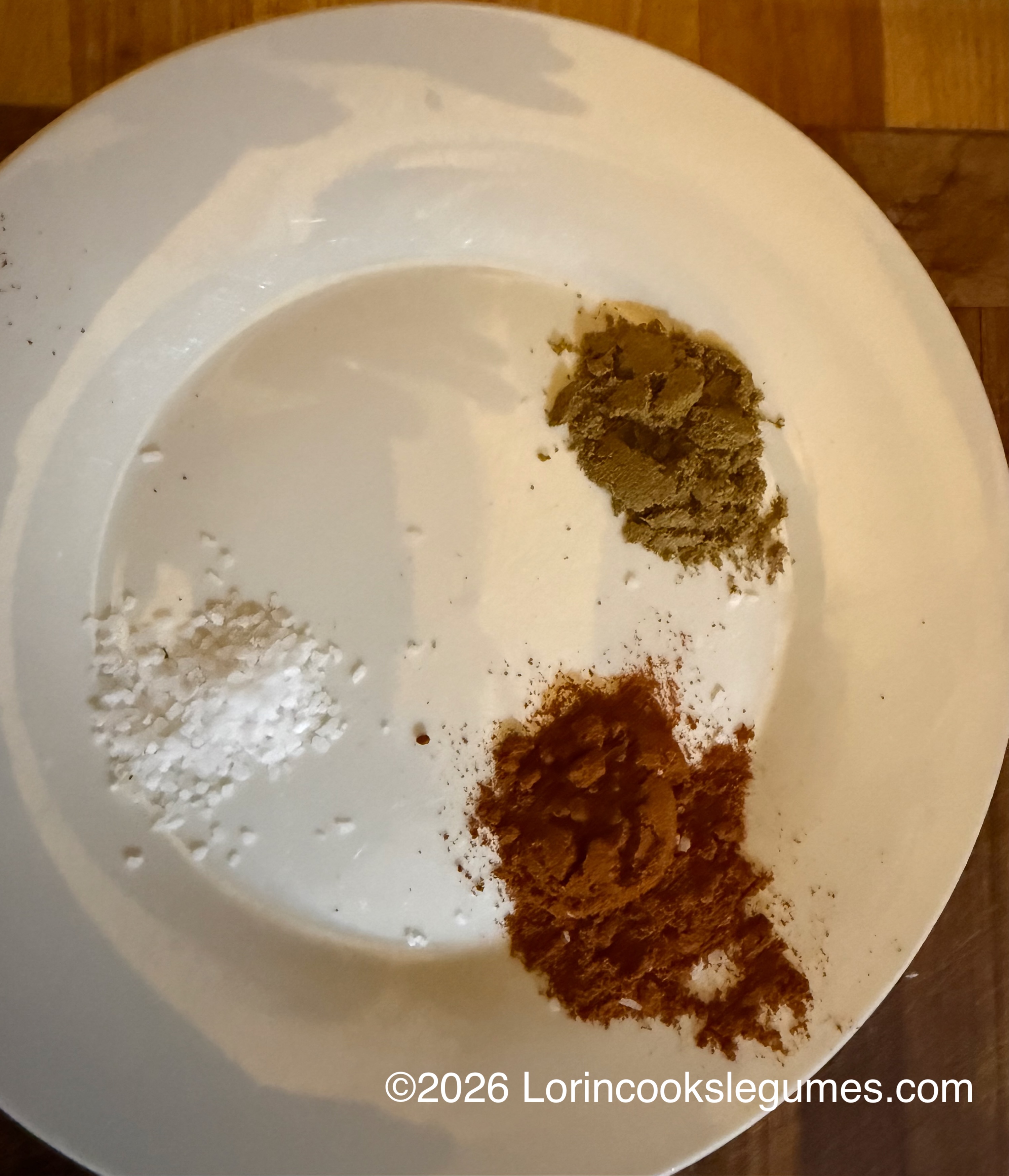 Piles of salt and two ground spices on a white plate. ©2026 Lorincookslegumes.com
