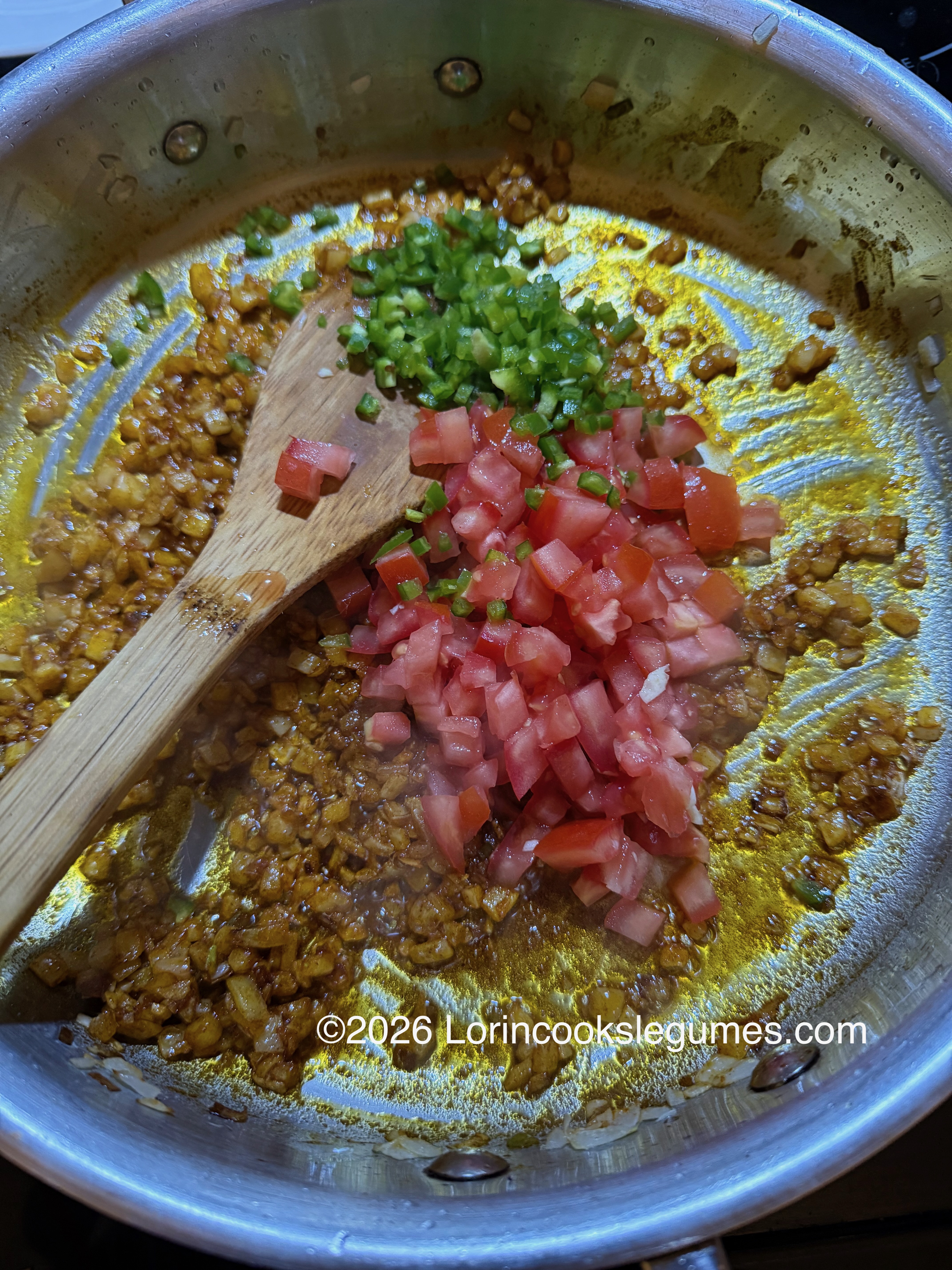 Diced tomato and jalapeño have been added to a pan with a mixture of onions and spices.