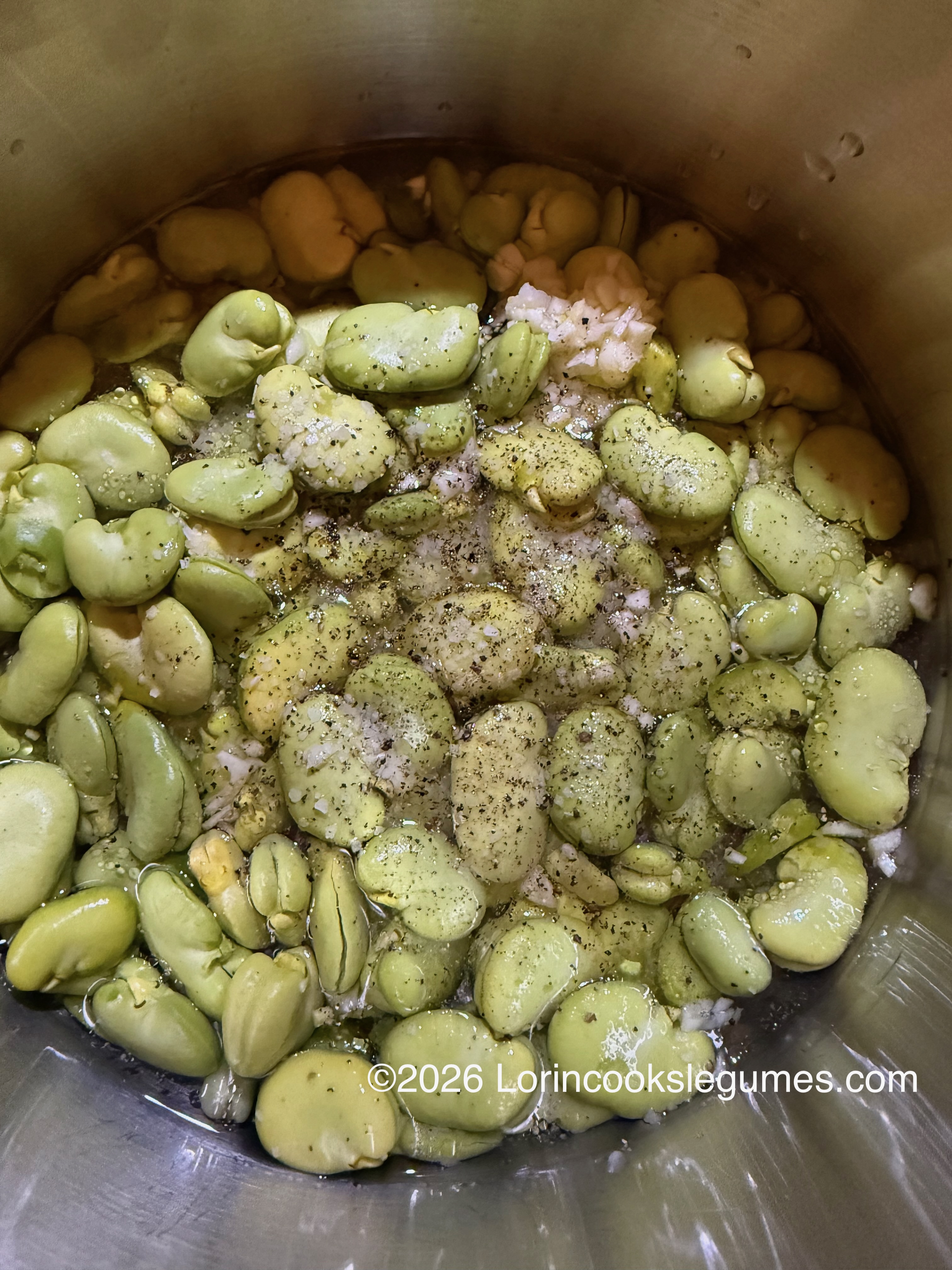 Broad beans in water with salt, pepper, and minced garlic in a pot