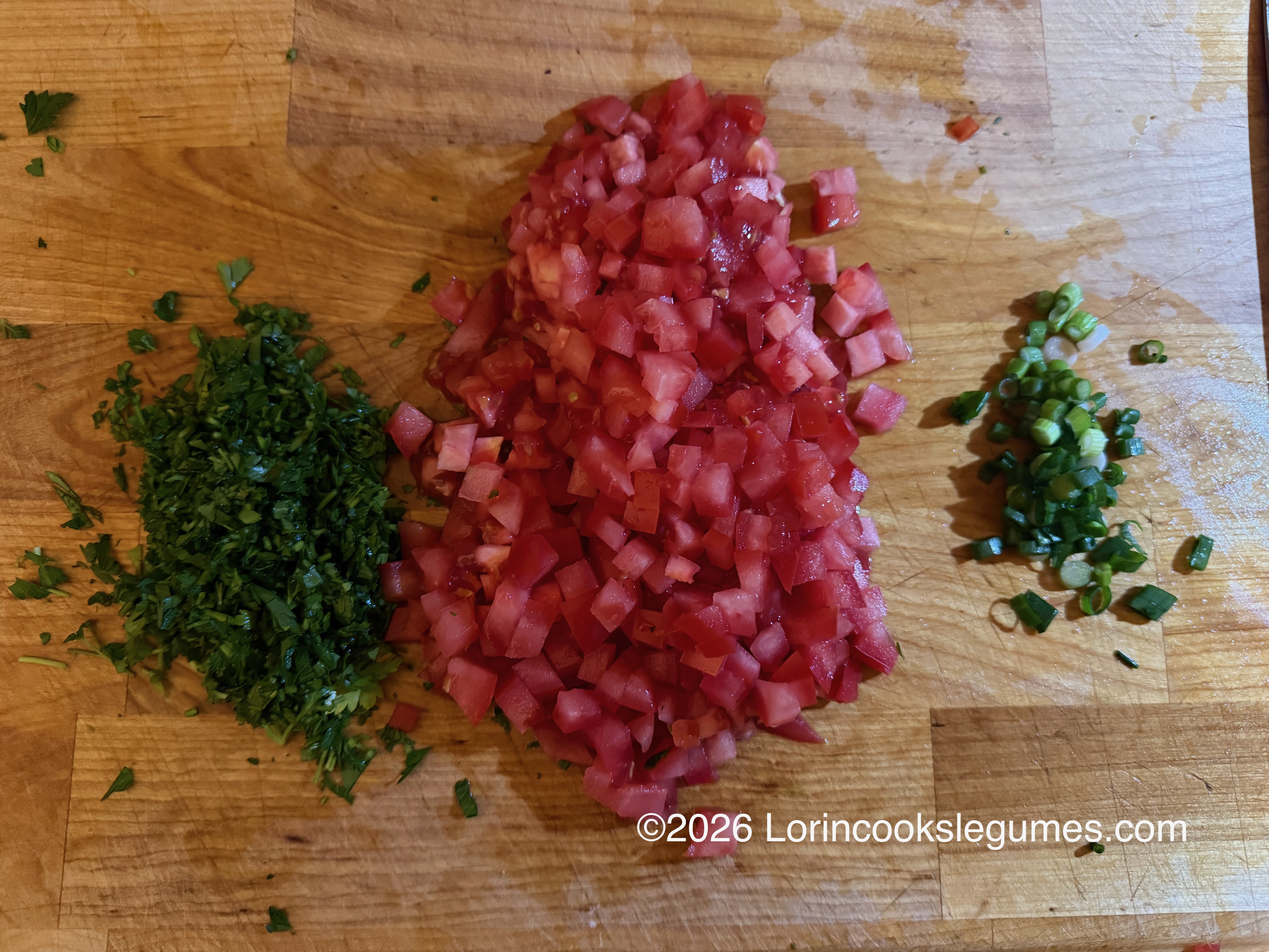IMG_9948 Chopped green parsley, diced red tomatoes, and sliced green onions on a wooden cutting board