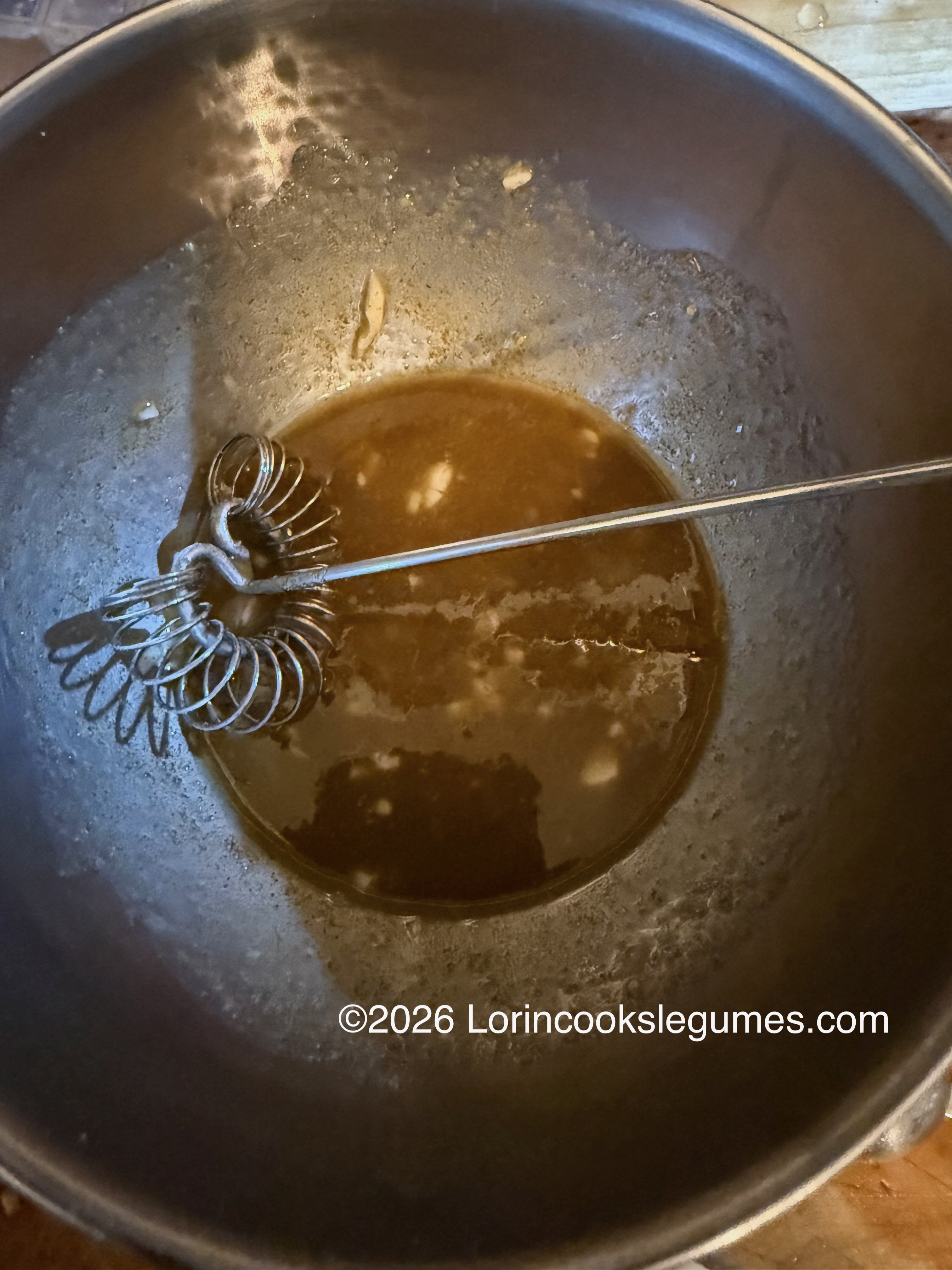 IMG_9951 Metal bowl with a small amount of brown salad dressing, and a stainless steel spiral whisk inside