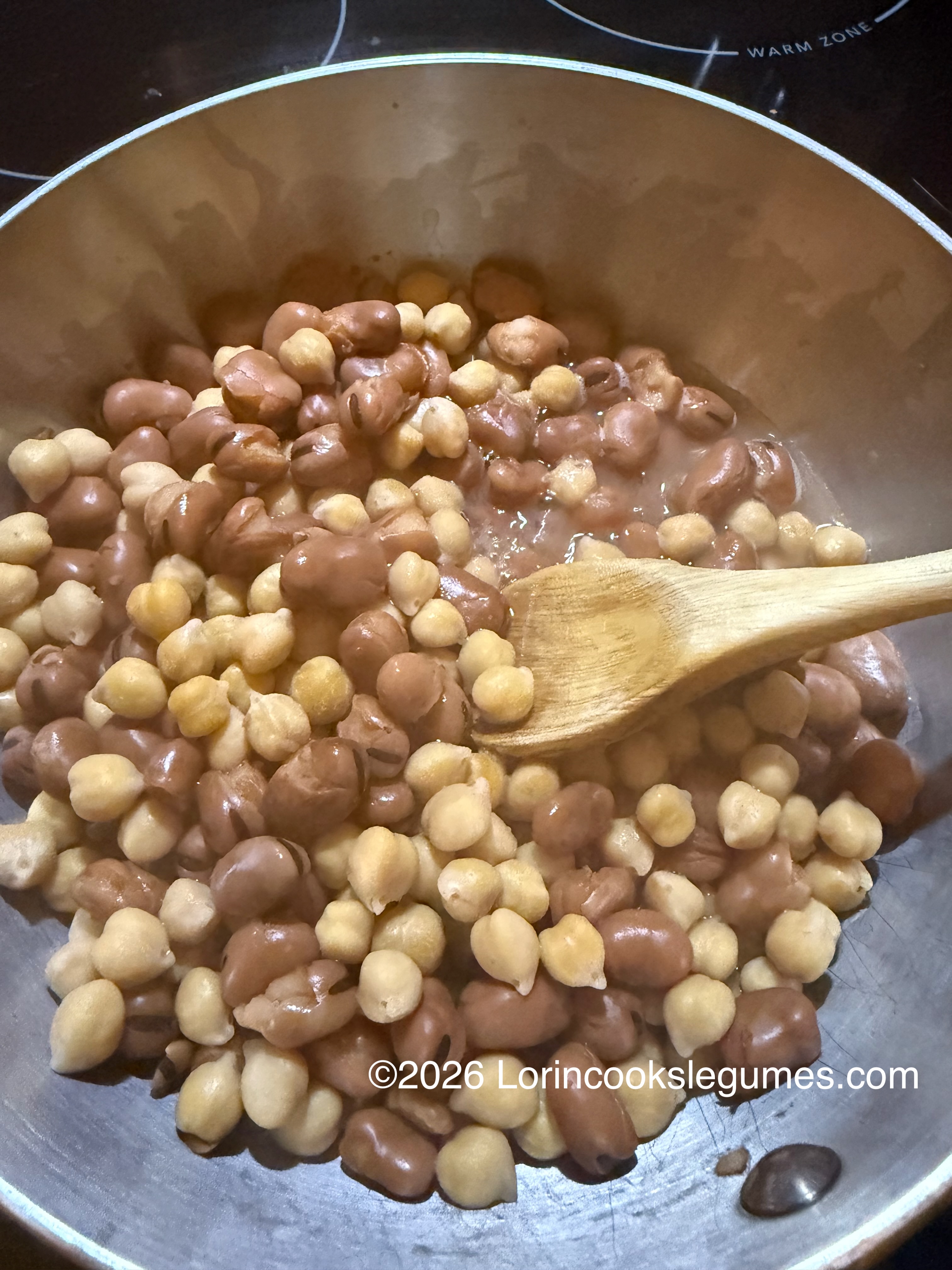 IMG_9952 fava beans and chickpeas simmering in a pot with a wooden spoon stirring