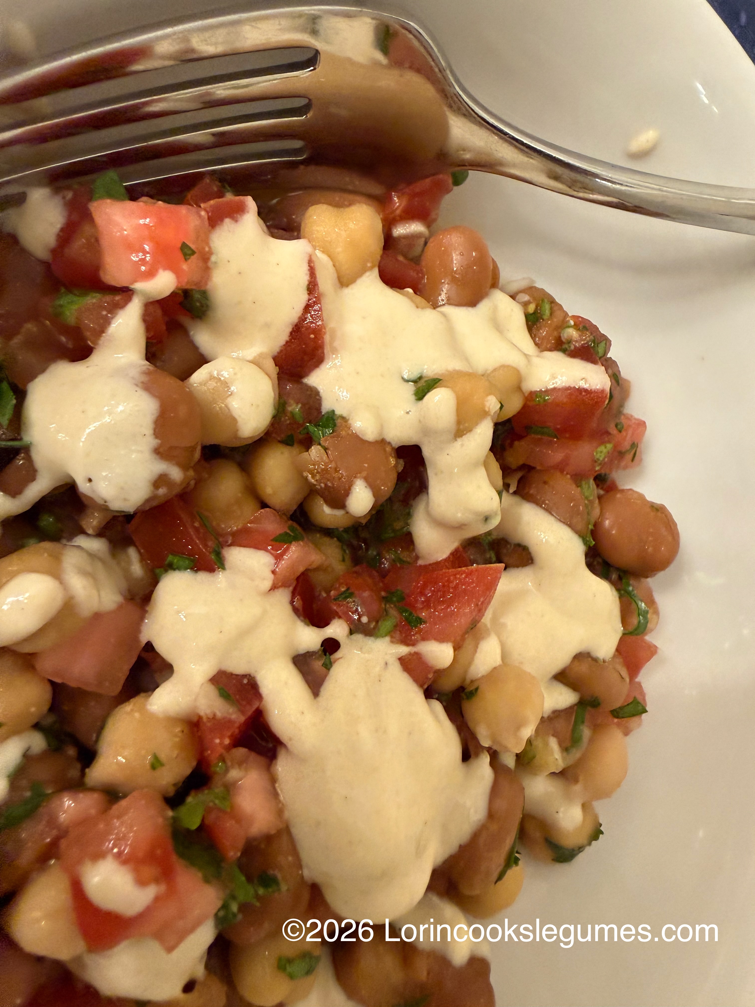 IMG_9967 Chickpea and fava bean salad with chopped tomatoes and herbs, topped with creamy dressing and a silver fork