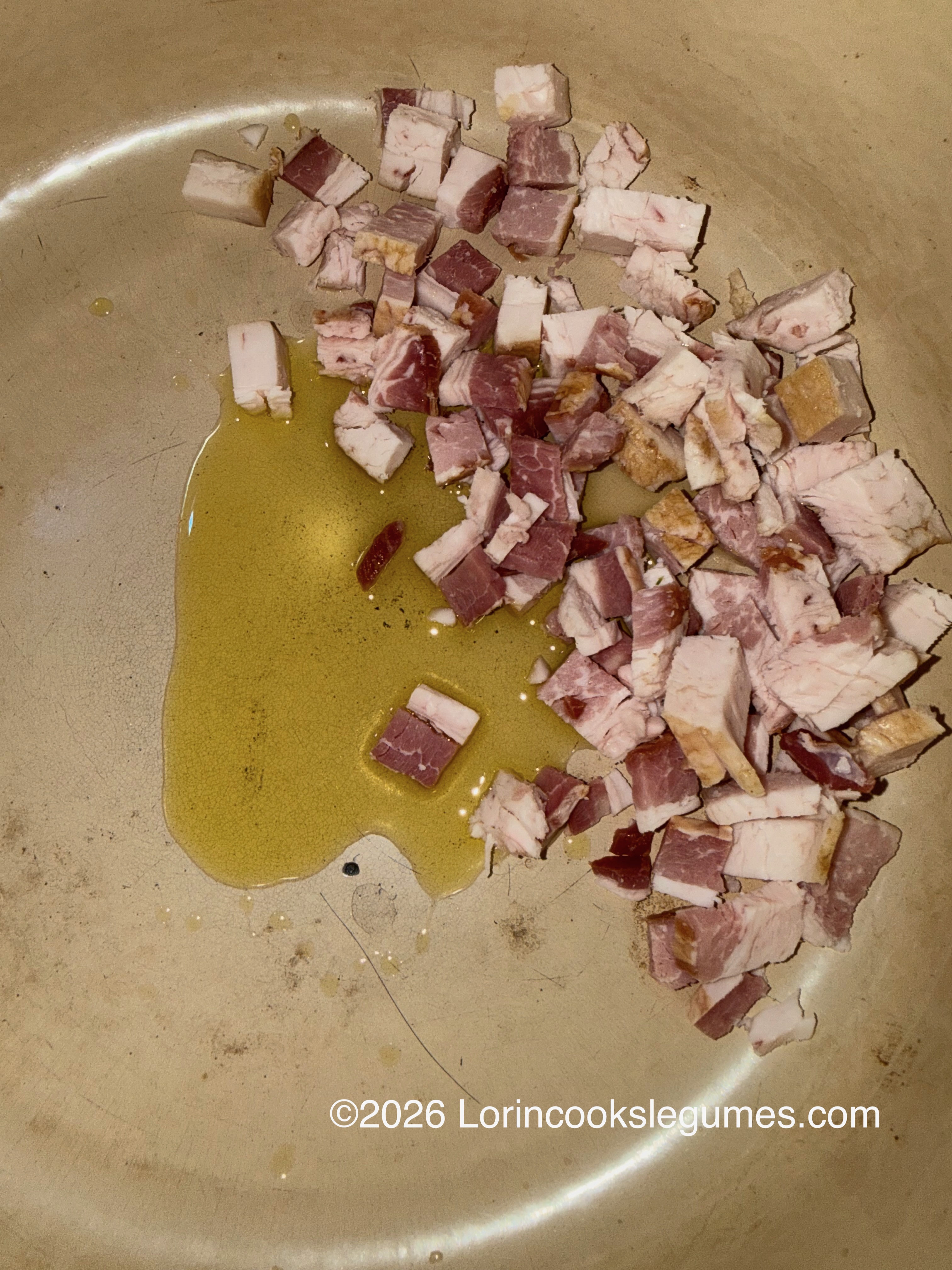 Cubed bacon frying in oil in a pan
