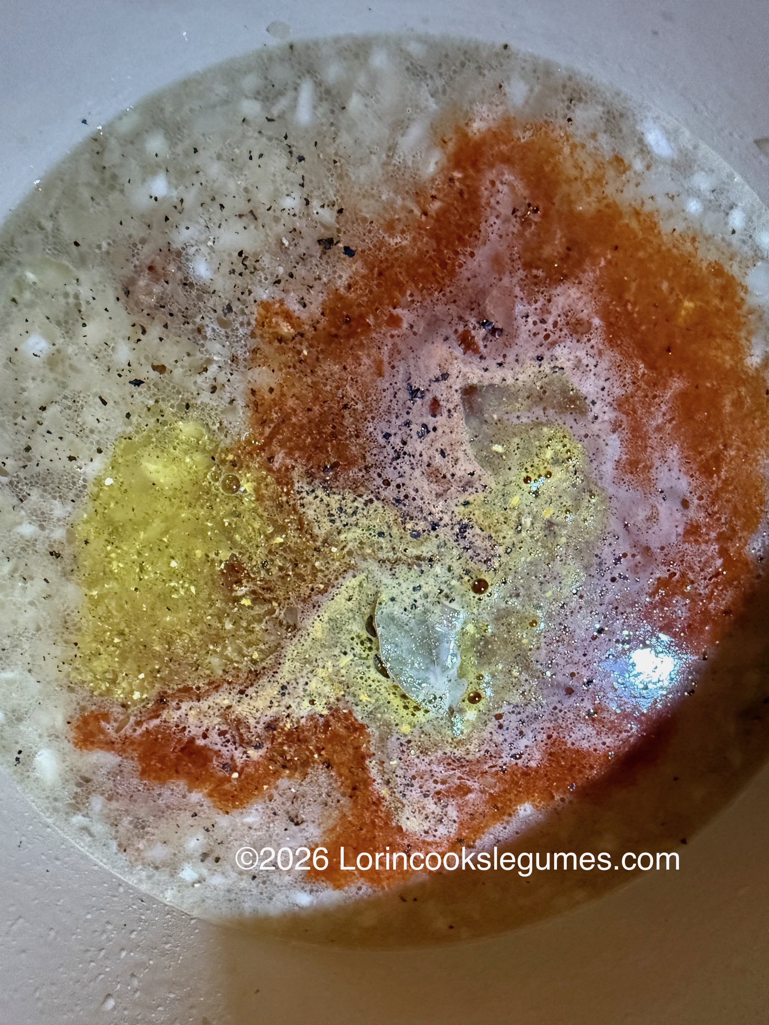 Close-up of cooking spices and water in a pan with a reddish and yellowish mixture