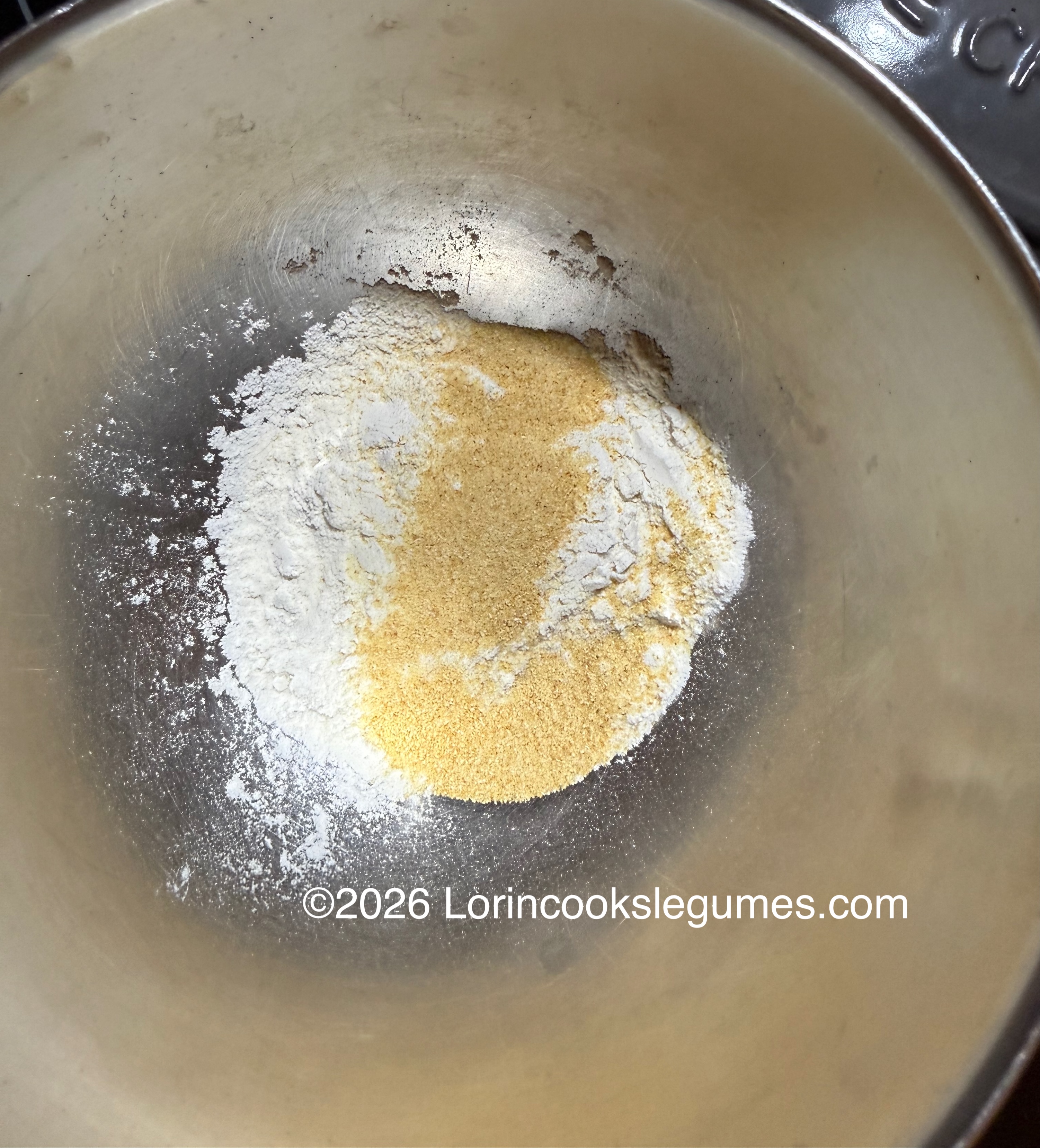 Flour and garlic powder in a metal mixing bowl