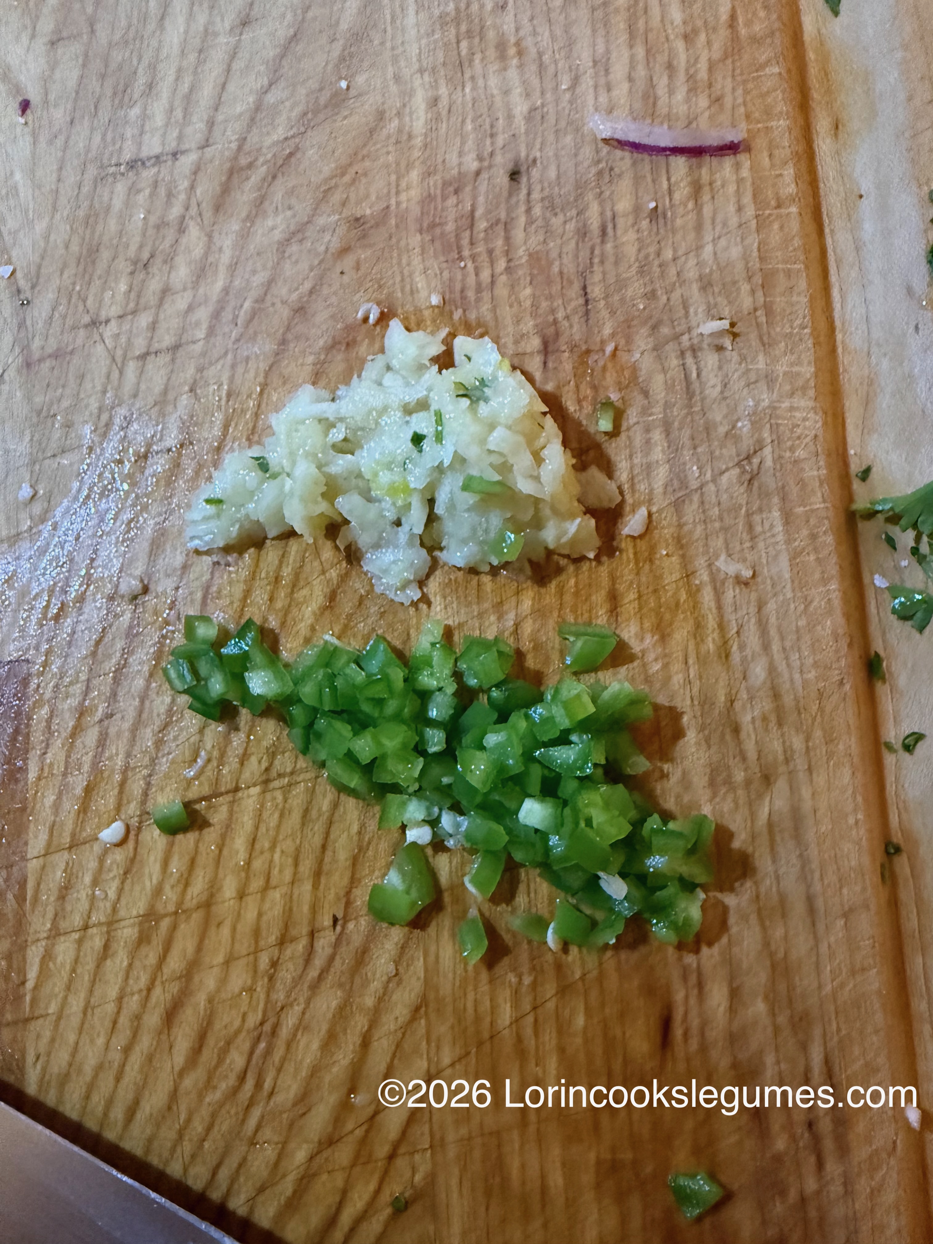 Mashed garlic and diced green chili on a wooden cutting board