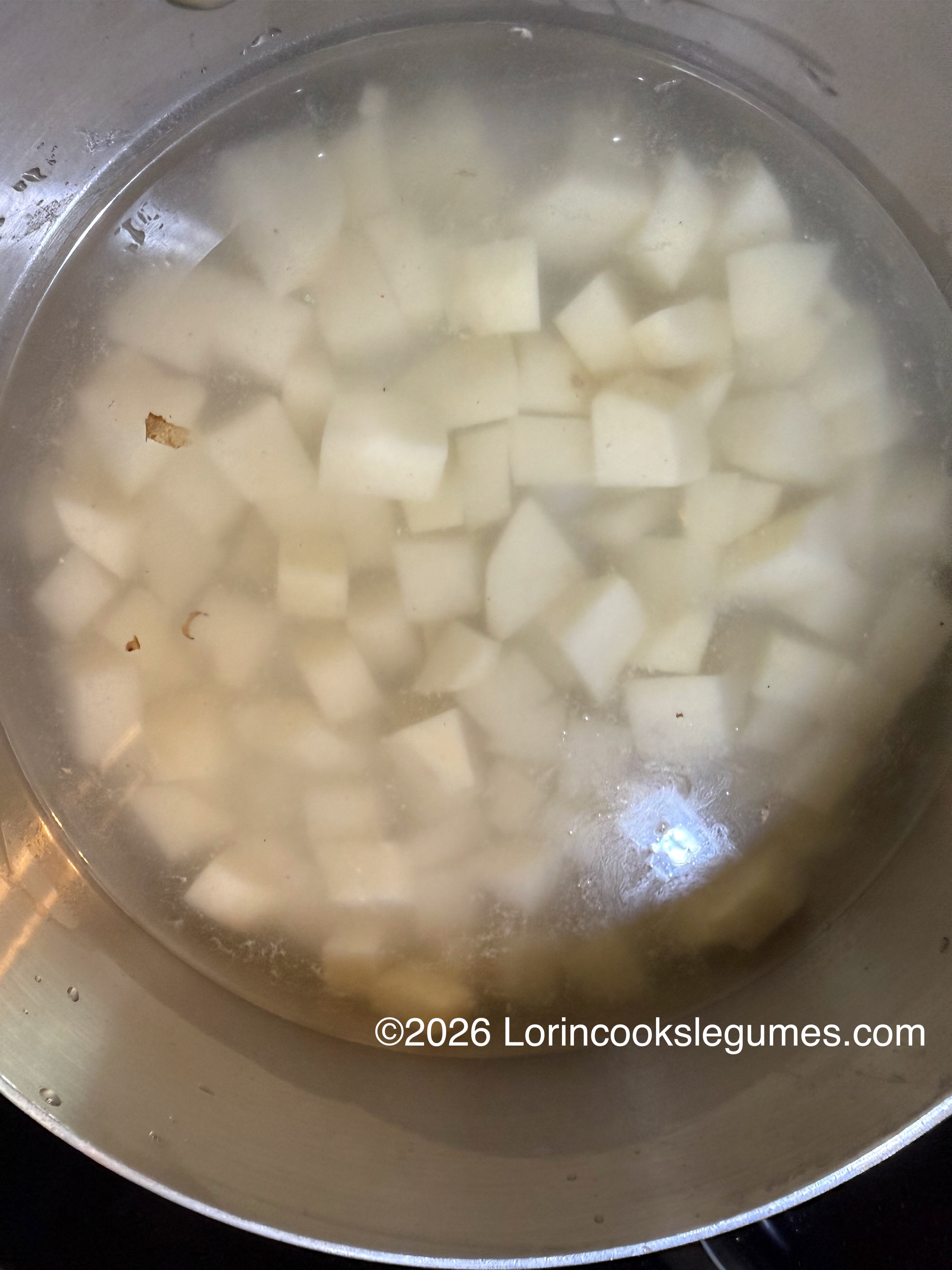 Diced white potatoes in water inside a metal pot