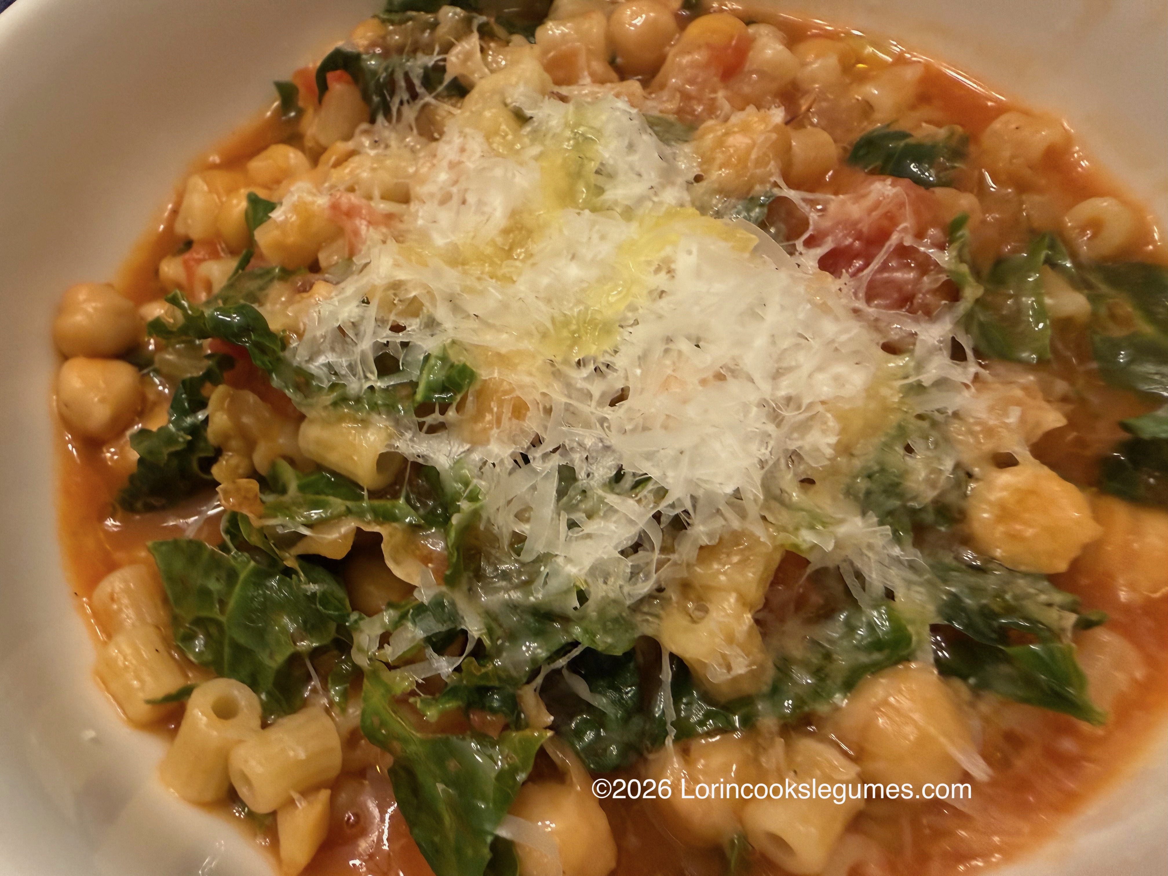 IMG_0230 Close-up of a bowl of pasta and chickpeas with greens, tomatoes, and cheese