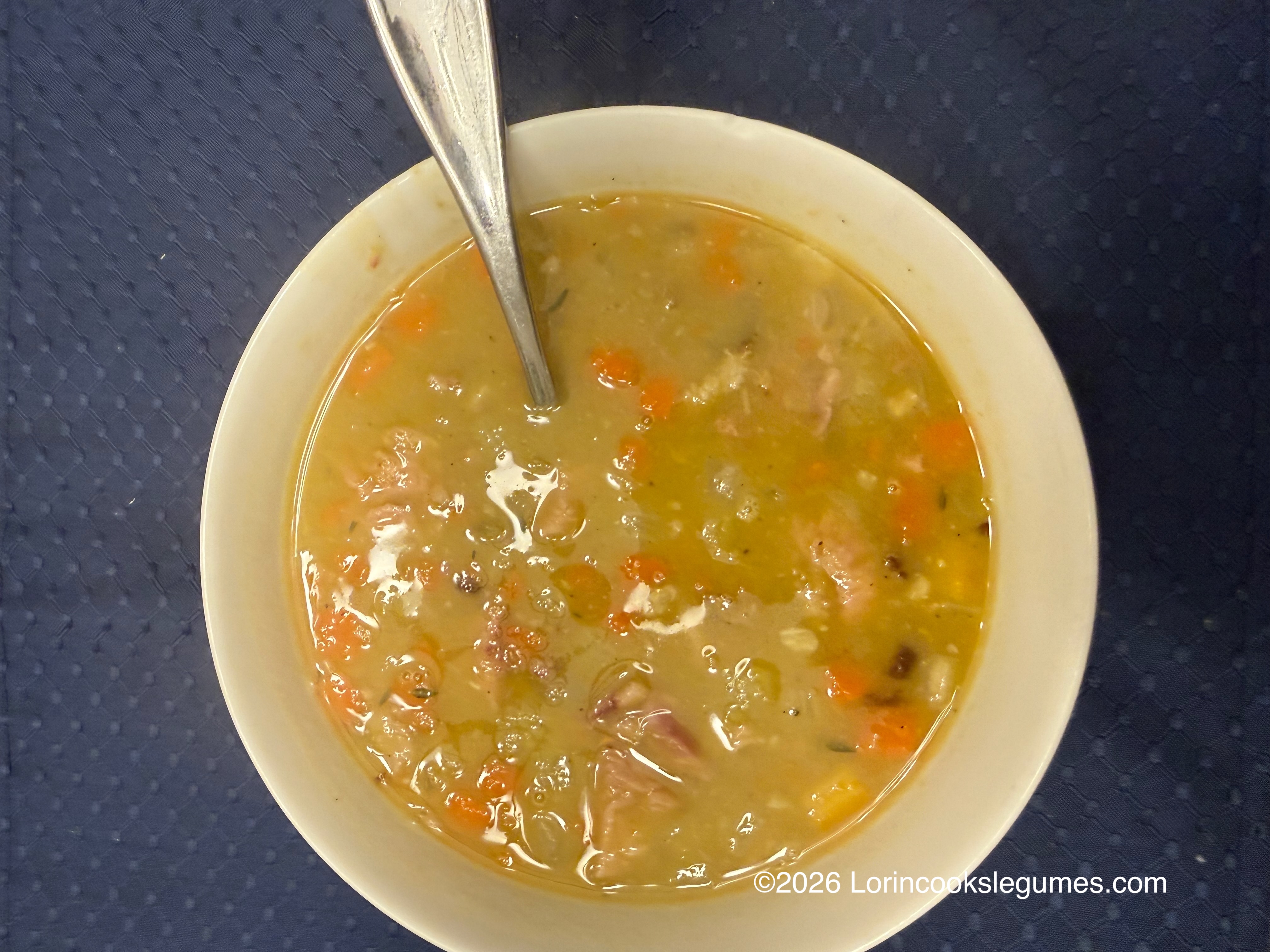 Close-up of a bowl of split pea soup with a spoon.